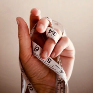 Hand mit Maßband Symbol für Messung und psychologische Tests