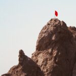 Berggipfel mit roter Fahne – Symbolbild für das Bewältigen schwieriger Lebensphasen und das Durchhalten in psychischen Krisen.