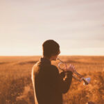 Junger Erwachsener spielt Trompete im Abendlicht – Symbolbild für Selbstfindung, Orientierung und emotionale Entwicklung in der Psychotherapie.